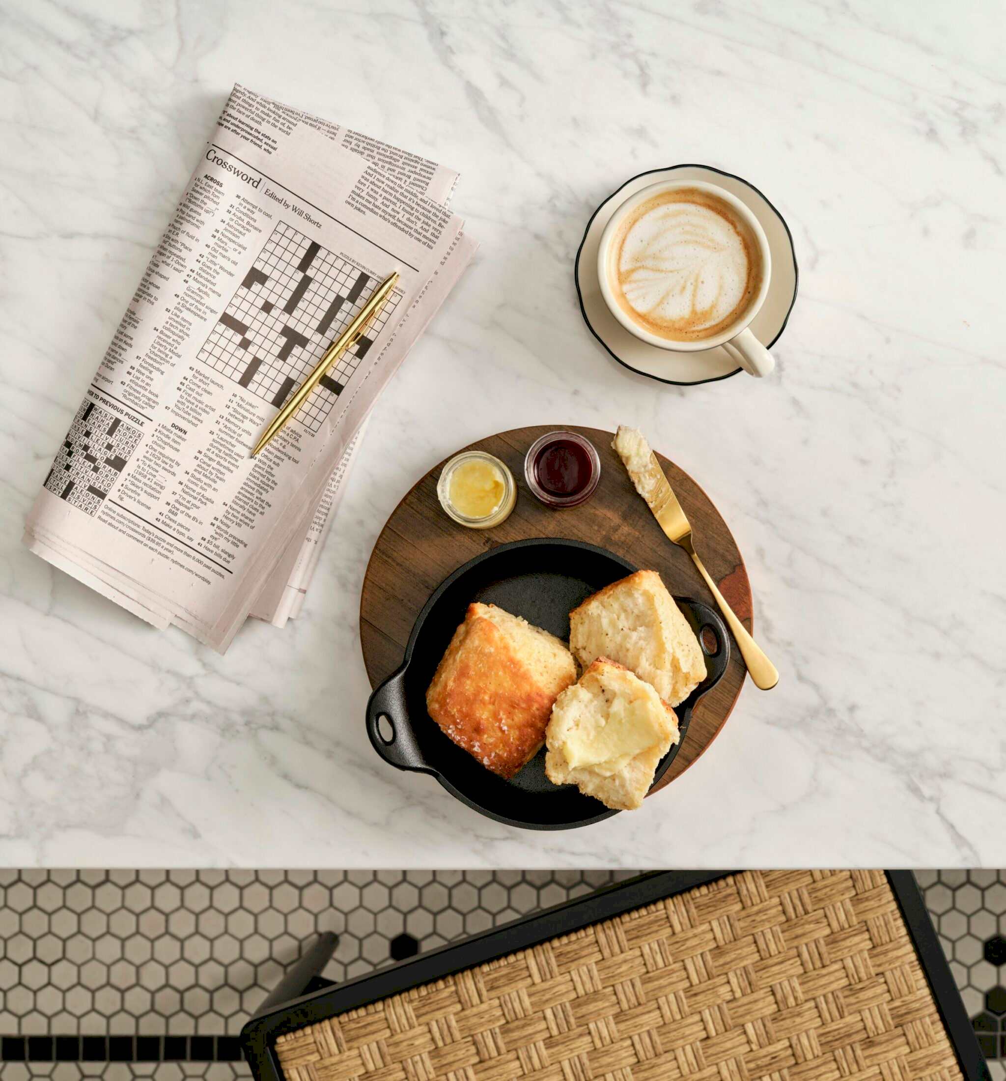 Biscuits and a cappuccino next to a crossword puzzle on a marble table